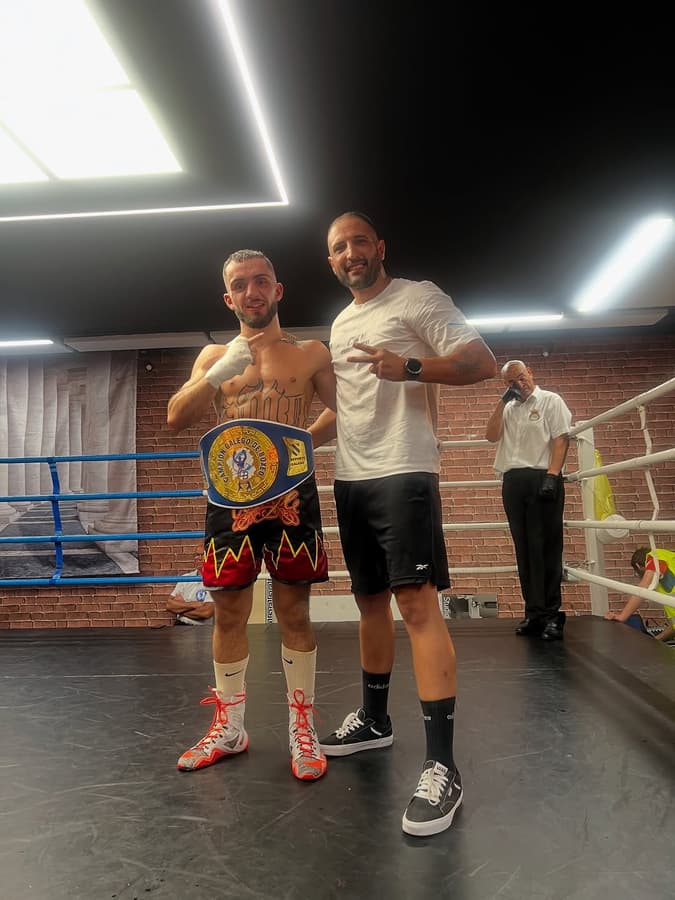 Dos peleadores del club posando en el ring con sus cinturones